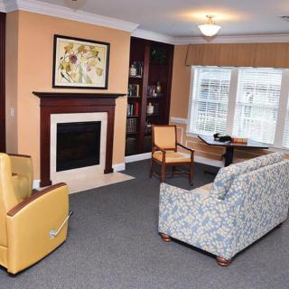 A cozy living room with a fireplace, seating area, and large window.