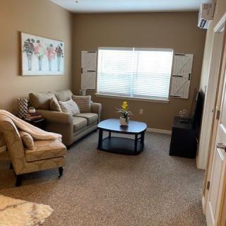 A cozy living room with a sofa, armchair, and coffee table under a large window.