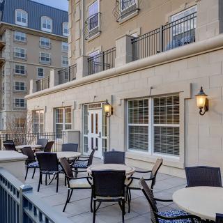A stylish outdoor patio area with tables and chairs adjacent to a residential building.
