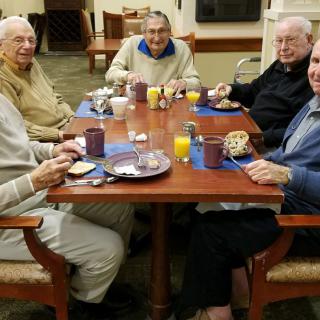 A group of seniors enjoying a meal together at a dining table.