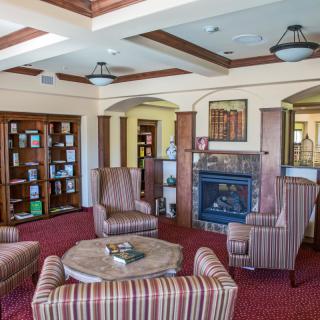 A cozy reading room with a fireplace and comfortable seating surrounded by bookshelves.