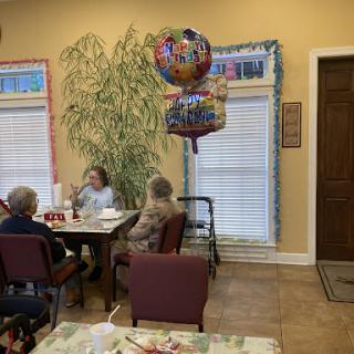 A cheerful gathering of seniors celebrating with balloons in a cozy community space.