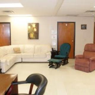 A cozy living room with a white sectional couch, a green chair, and a red recliner.