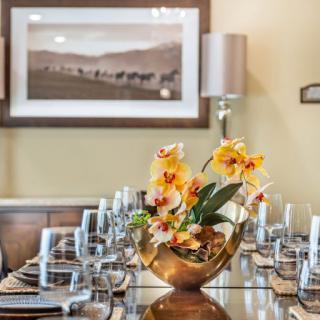 An elegantly set dining table with a centerpiece of vibrant orchids.