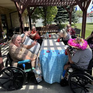 A joyful gathering of elderly individuals enjoying a sunny day outdoors, surrounded by colorful decorations.