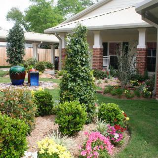 A well-maintained garden with a variety of plants and flowers in front of a house.
