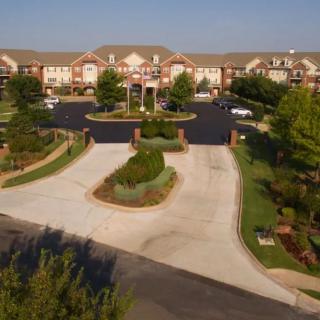 Aerial view of a large building with a landscaped entrance and parking lot.