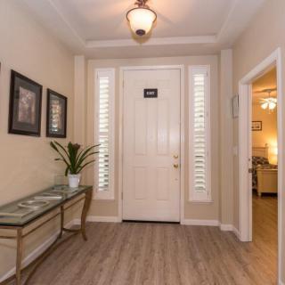 A welcoming entryway with a stylish table and plant, hardwood floors, and bright lighting.