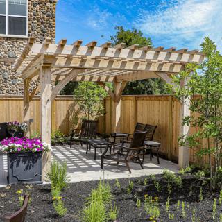 A cozy backyard patio with a pergola, complete with outdoor furniture and lush greenery.