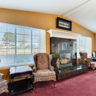 A cozy living room featuring armchairs by a fireplace with large windows.