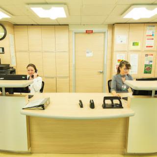 Two employees working at a reception desk in an office environment.