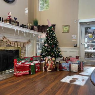 A cozy living room decorated for Christmas with a beautifully adorned tree and an array of gifts by the fireplace.
