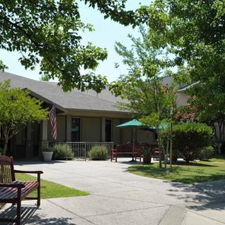 A peaceful outdoor area with benches and a building surrounded by trees.