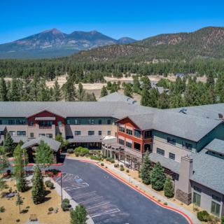 A scenic view of a resort nestled in a forest with mountains in the background.