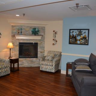 A cozy living room with a fireplace, sofa, and armchairs on wood flooring.