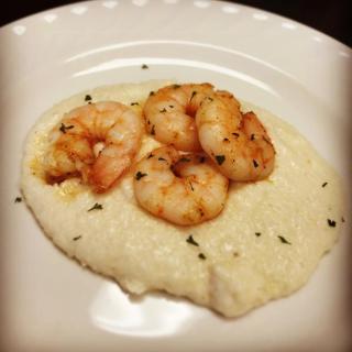 Delicious shrimp served over creamy grits on a white plate.