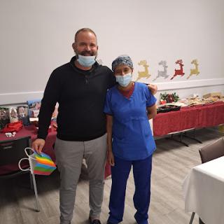 A healthcare professional and a guest pose together at a celebratory event, both wearing masks.