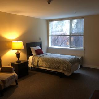 A cozy bedroom with a single bed and a warm lamp by the window.