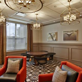 A modern lounge with elegant chandeliers, red armchairs, and a round table.