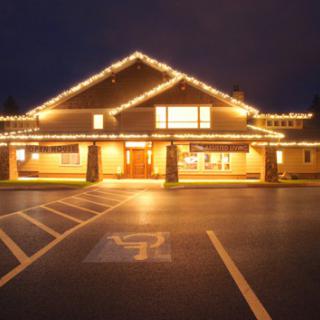 A well-lit building at night with lights highlighting its architecture, set beside an empty parking lot.