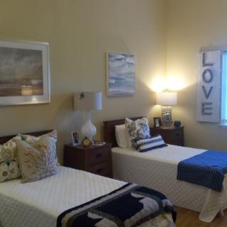 A cozy bedroom featuring twin beds with decorative pillows, warm lighting, and wall art.