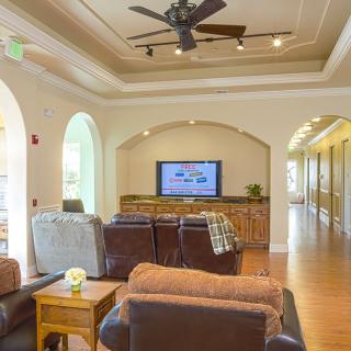 A modern living room with comfortable seating and a TV, illuminated by natural light.