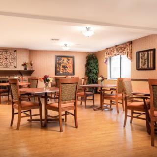 A cozy dining area with multiple tables and chairs, decorated with artwork and plants.