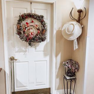 A cozy hallway featuring a wreath-adorned door and a decorative hat rack.
