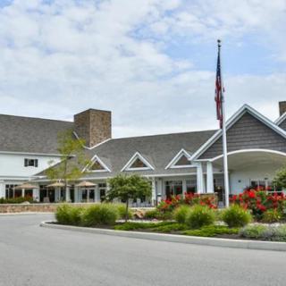 A scenic view of a large building with a flagpole, surrounded by landscaping and under a partly cloudy sky.