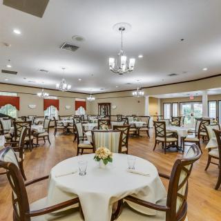 A spacious dining room with neatly arranged tables and chairs, featuring elegant chandeliers and decor.
