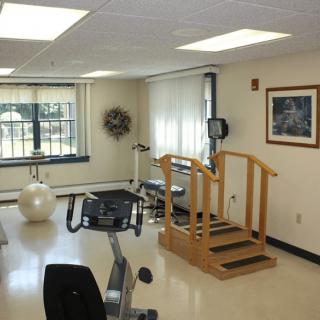 A rehabilitation room with various exercise equipment and a set of wooden steps.