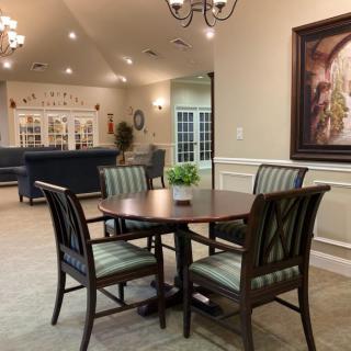 A cozy dining area with a table, chairs, artwork on the wall, and soft lighting.