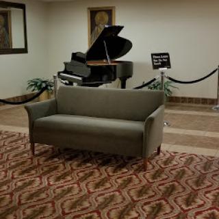 A cozy lobby area featuring a green sofa and a grand piano, adding an elegant touch to the space.