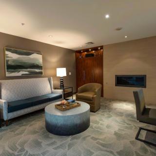 A modern living room with stylish furniture, including a sofa, armchair, and coffee table, complemented by a lamp and artwork on the wall.