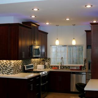 A modern kitchen with dark wood cabinets, stainless steel appliances, and stylish pendant lighting.