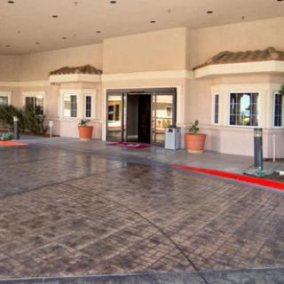 The entrance of a hotel with potted plants and a paved walkway.