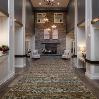 A luxurious living room with a tall stone fireplace and elegant chandeliers.