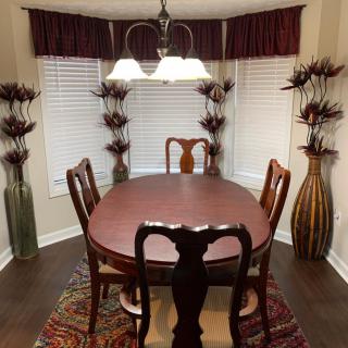 A classic dining room with a wooden table and chairs, accentuated by tall decorative vases and elegant lighting.