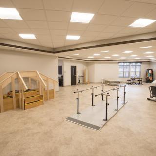 A spacious rehabilitation center with exercise equipment and handrails for physical therapy.