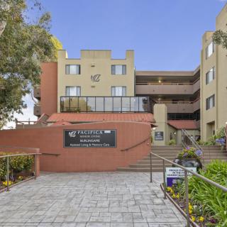 The entrance of an apartment complex featuring modern architecture and well-maintained landscaping.