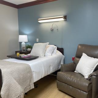 A cozy and well-lit bedroom featuring a comfortable bed, a reading chair, and decorative accents.