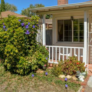 A cozy house with a small front porch and a garden adorned with blooming flowers.