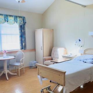 A clean and well-lit hospital room with a bed, table, and chairs.
