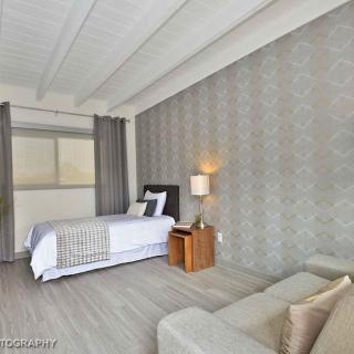 A modern bedroom with stylish decor, featuring a bed, bedside lamp, and sofa.