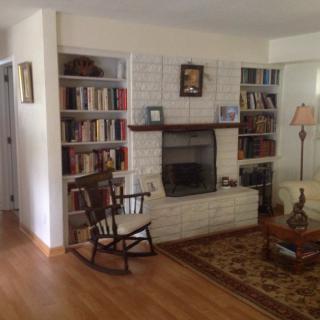 A cozy living room with a fireplace, rocking chair, and bookshelves.