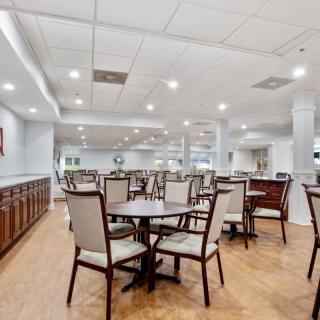 A spacious dining area with neatly arranged tables and chairs under bright lighting.