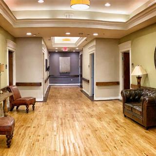 A well-lit hallway with wooden flooring and comfortable seating arrangements.