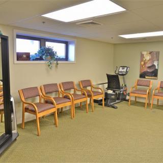 An empty waiting room with arranged chairs and a painting on the wall.