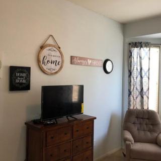 A cozy living room setup featuring a television, decorative wall art, and a comfortable chair by the window.