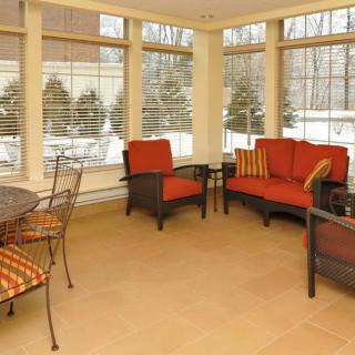 A cozy sunroom featuring comfortable seating and large windows with outdoor views.